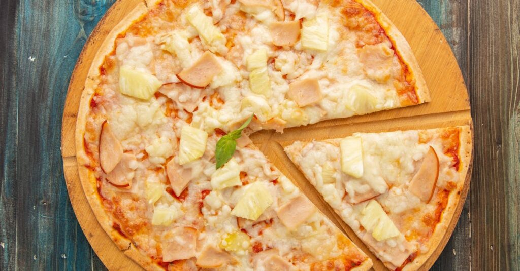 Top view of a Hawaiian pizza with pineapple and ham on a wooden board, capturing the essence of Italian cuisine.