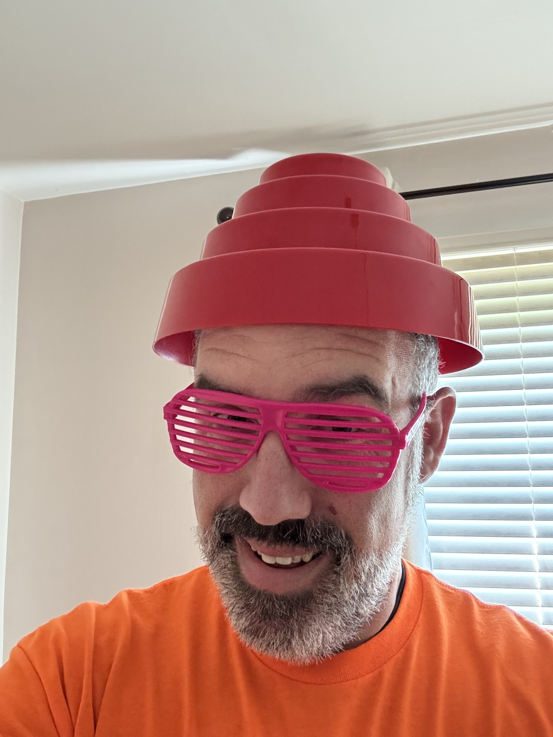 Seth dressed in bright orange shirt, pink shutter glasses and a Devo band hat