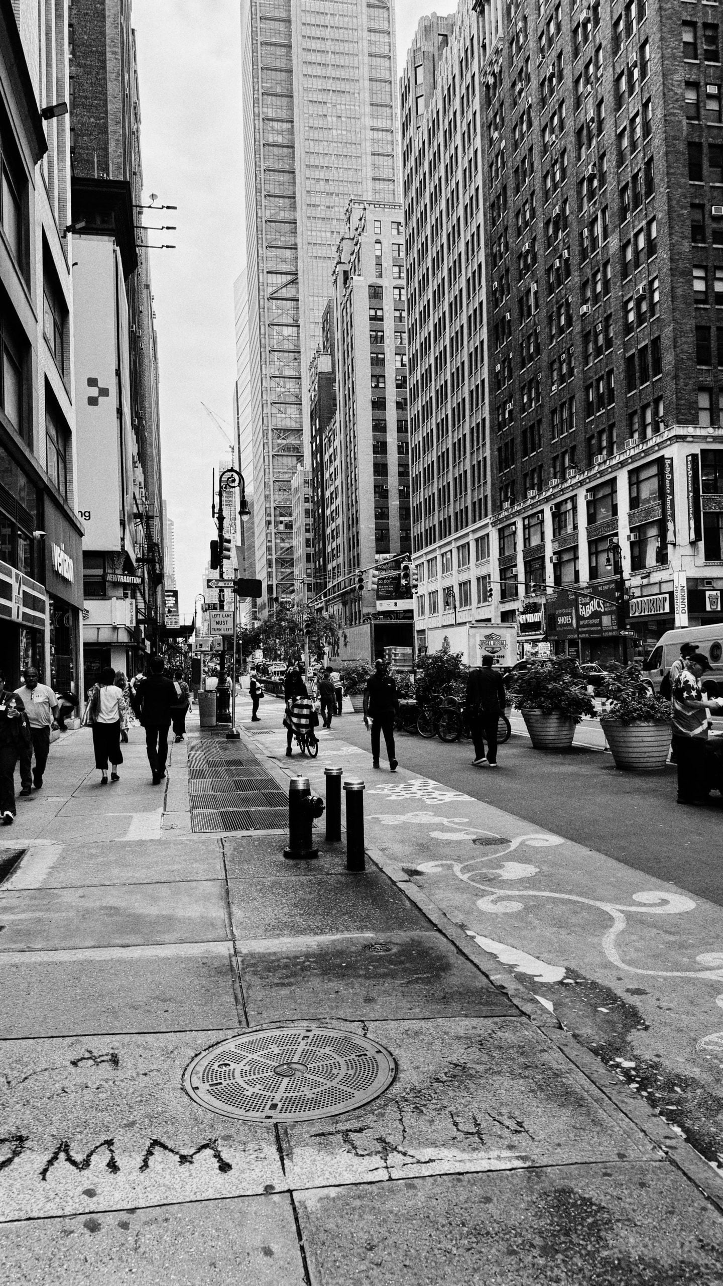 Black and white photo taken on an iPhone 15 pro. 8th Avenue looking north. People and cars and bikes all going about their business. Neat shot if you ask me.