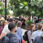 A large group of people gathered indoors at a conference, engaging in conversation and wearing name badges.